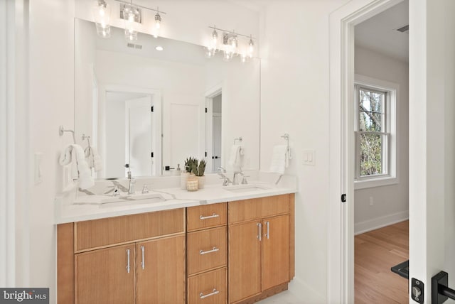 full bathroom featuring double vanity, visible vents, a sink, and wood finished floors