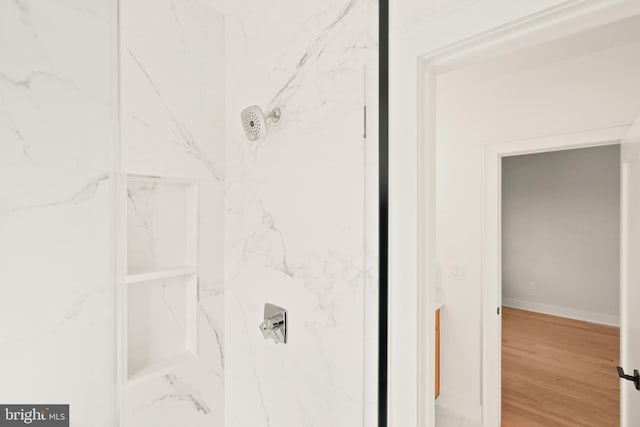 bathroom featuring baseboards, a marble finish shower, and wood finished floors