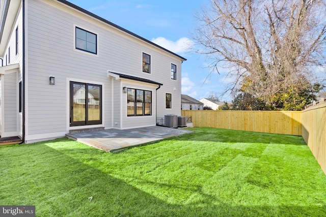 rear view of house featuring central AC unit, a lawn, a patio area, and a fenced backyard