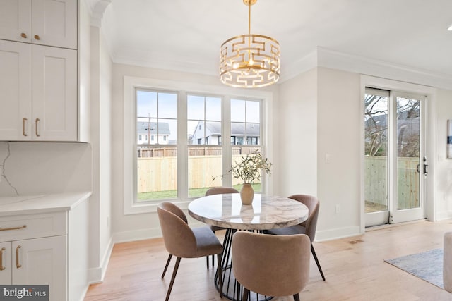 dining space with ornamental molding, light wood-style floors, baseboards, and an inviting chandelier