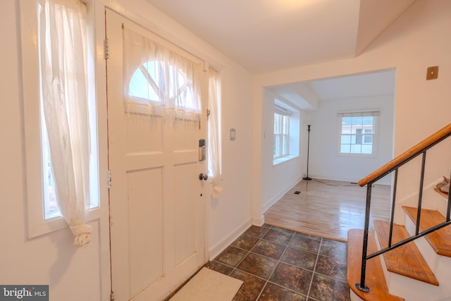 foyer featuring stairs and baseboards