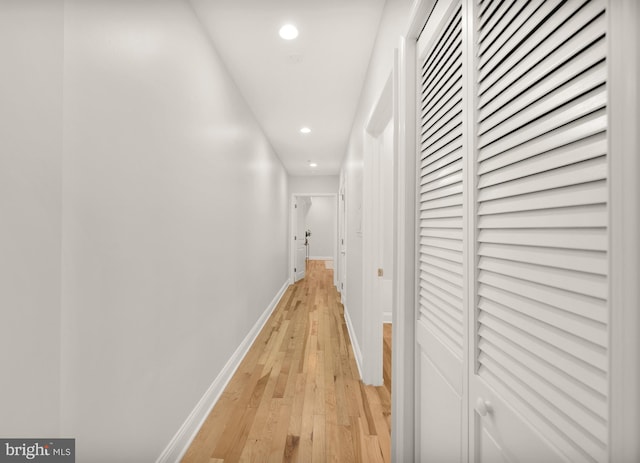 hall featuring light wood-type flooring, baseboards, and recessed lighting