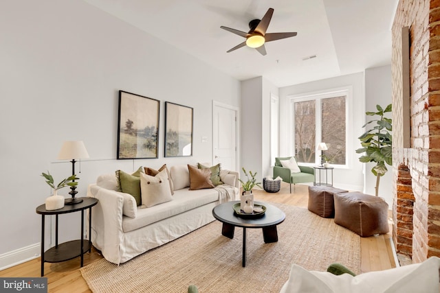 living area featuring a ceiling fan, baseboards, visible vents, and wood finished floors