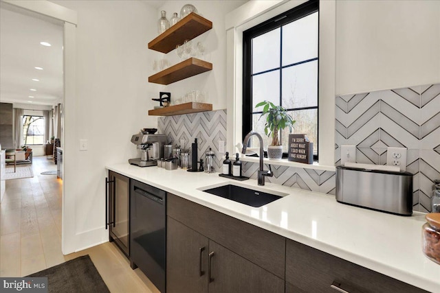 bar with light wood-style floors, backsplash, a sink, and recessed lighting