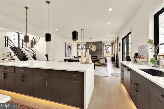 kitchen featuring open floor plan, light countertops, light wood-style floors, pendant lighting, and a sink