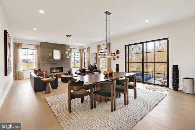 dining space with light wood finished floors, a fireplace, baseboards, and recessed lighting