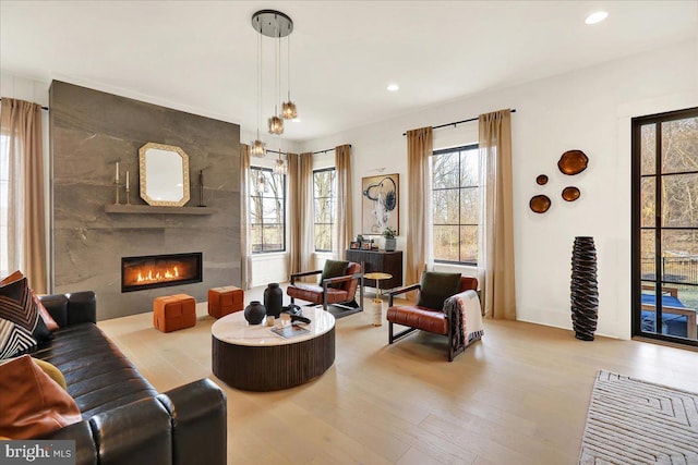 living area featuring recessed lighting, a large fireplace, and light wood-style flooring