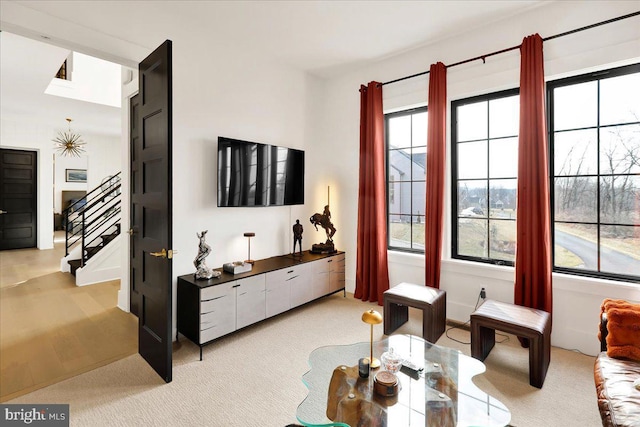 living room with a healthy amount of sunlight, stairs, and light carpet