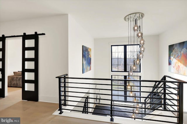 stairway featuring a chandelier, a barn door, and baseboards