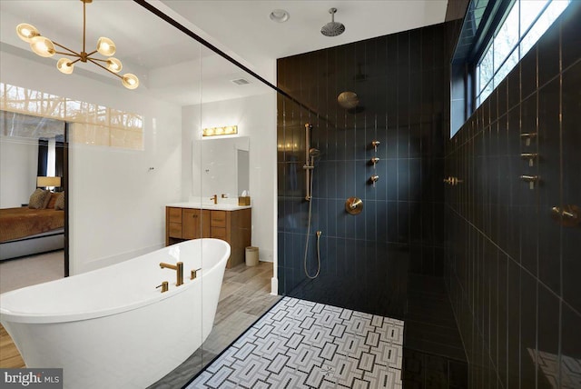 bathroom with a notable chandelier, a freestanding bath, connected bathroom, a tile shower, and vanity