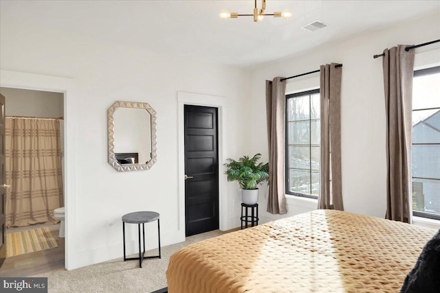 bedroom with a chandelier, light colored carpet, and visible vents