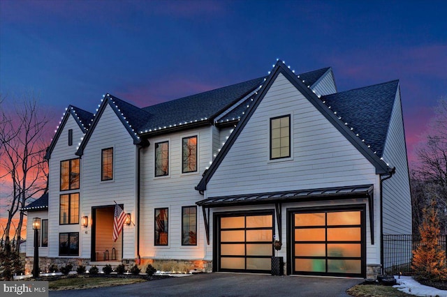 view of front of home featuring metal roof, an attached garage, a shingled roof, driveway, and a standing seam roof