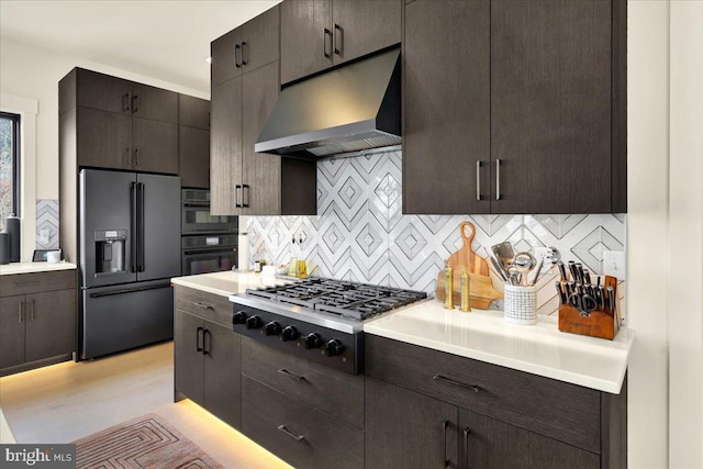 kitchen with stainless steel gas stovetop, high quality fridge, light countertops, and under cabinet range hood