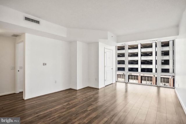 unfurnished living room with dark wood-style floors, baseboards, and visible vents