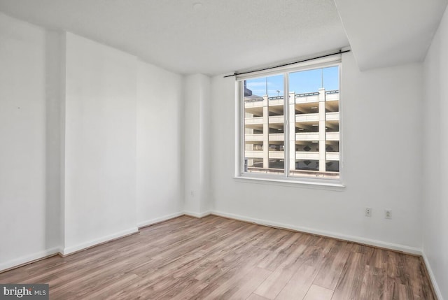 spare room with baseboards and wood finished floors