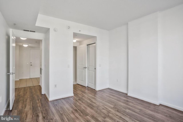 unfurnished bedroom with dark wood-style floors, a closet, visible vents, and baseboards