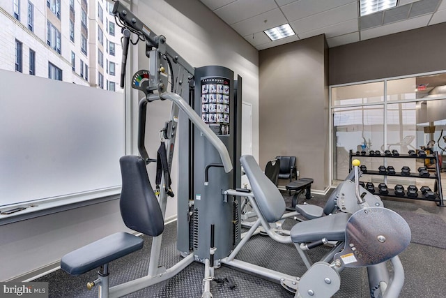 exercise room featuring baseboards and a drop ceiling