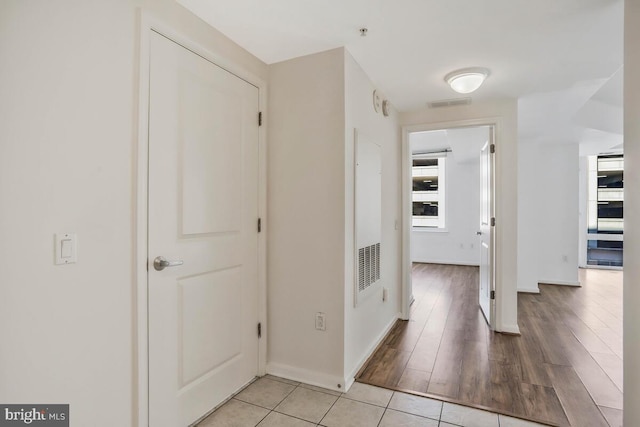 corridor with baseboards, plenty of natural light, visible vents, and light wood-style floors