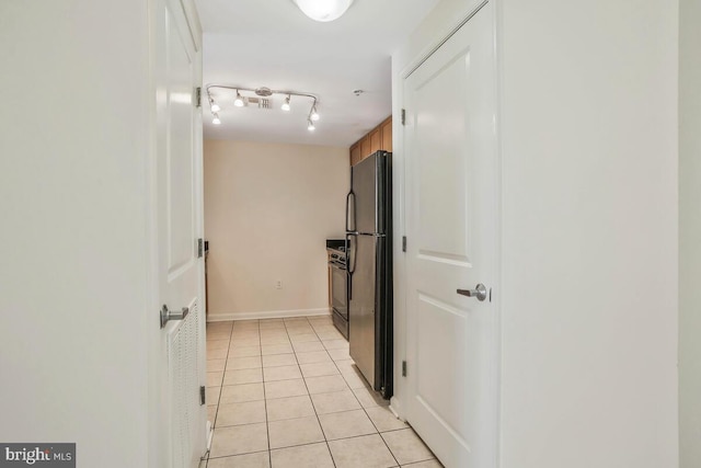 hall with light tile patterned flooring, rail lighting, and baseboards