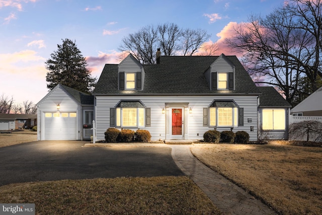 cape cod-style house with a garage, a yard, aphalt driveway, and roof with shingles