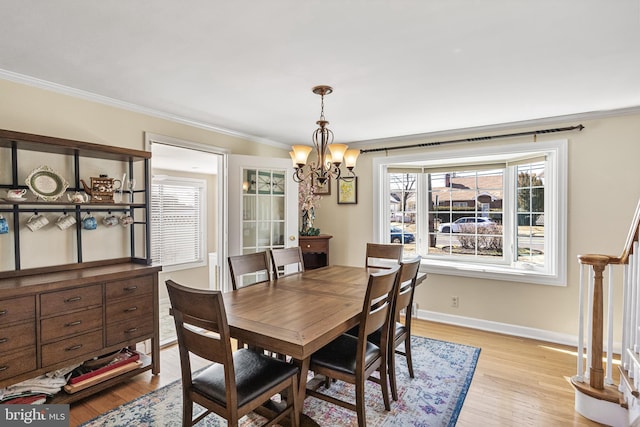 dining area featuring ornamental molding, light wood-type flooring, baseboards, and an inviting chandelier