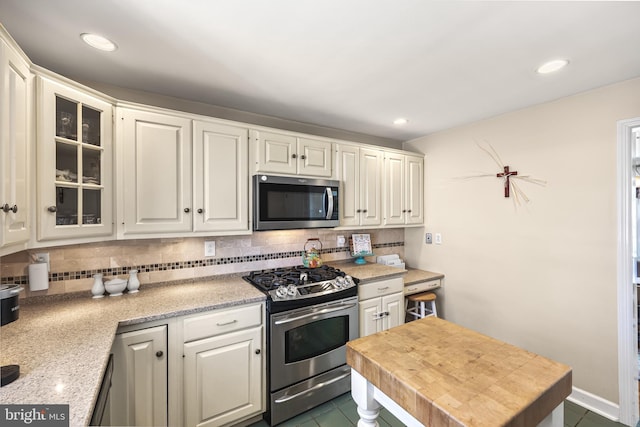 kitchen with light countertops, appliances with stainless steel finishes, white cabinetry, and decorative backsplash