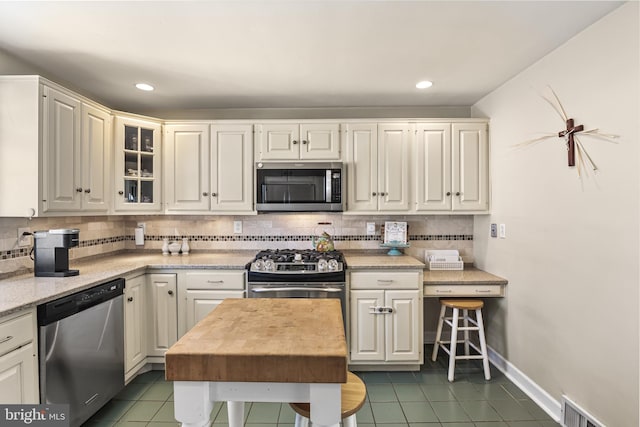 kitchen with stainless steel appliances, visible vents, backsplash, tile patterned flooring, and baseboards