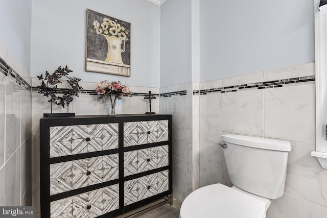 half bath featuring toilet and tile walls