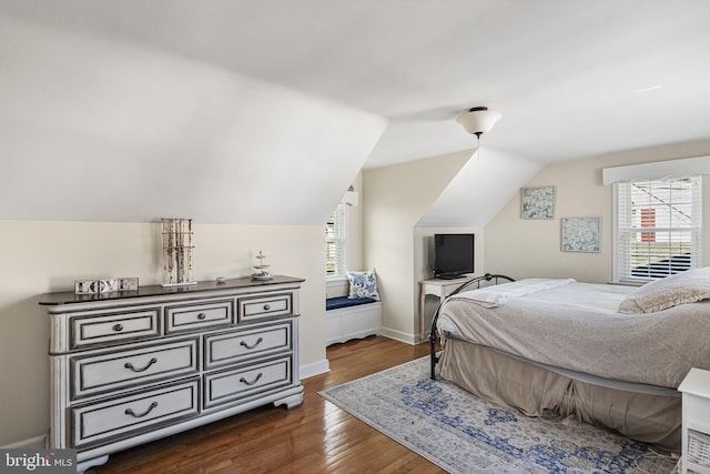 bedroom featuring dark wood-type flooring, lofted ceiling, and baseboards