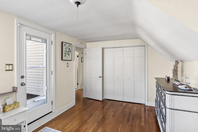 interior space with vaulted ceiling, a closet, dark wood finished floors, and baseboards