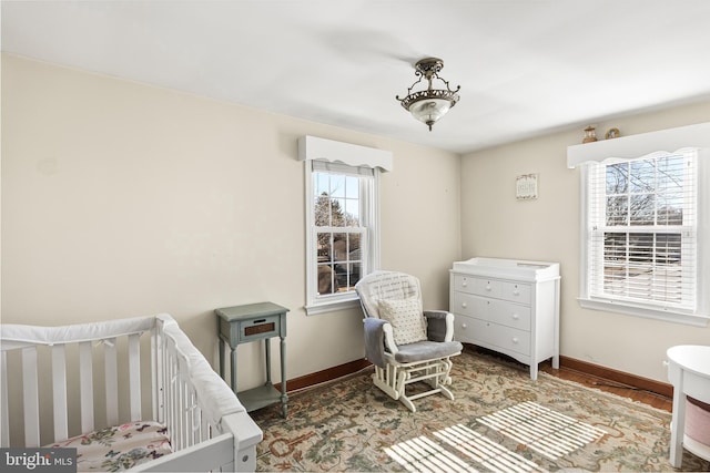 bedroom featuring a crib, wood finished floors, and baseboards