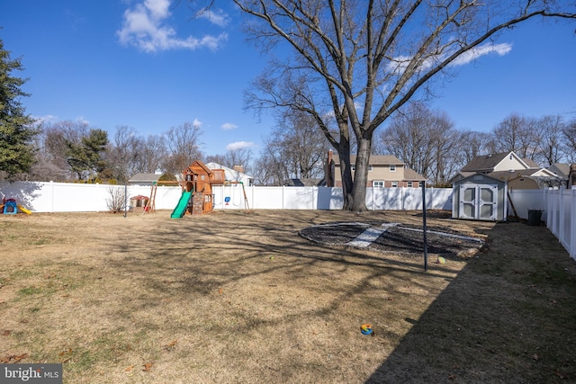 view of yard featuring a fenced backyard, a storage unit, a playground, and an outdoor structure