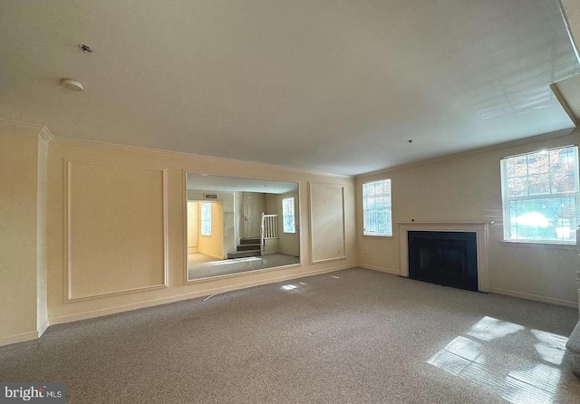 unfurnished living room featuring crown molding and carpet flooring