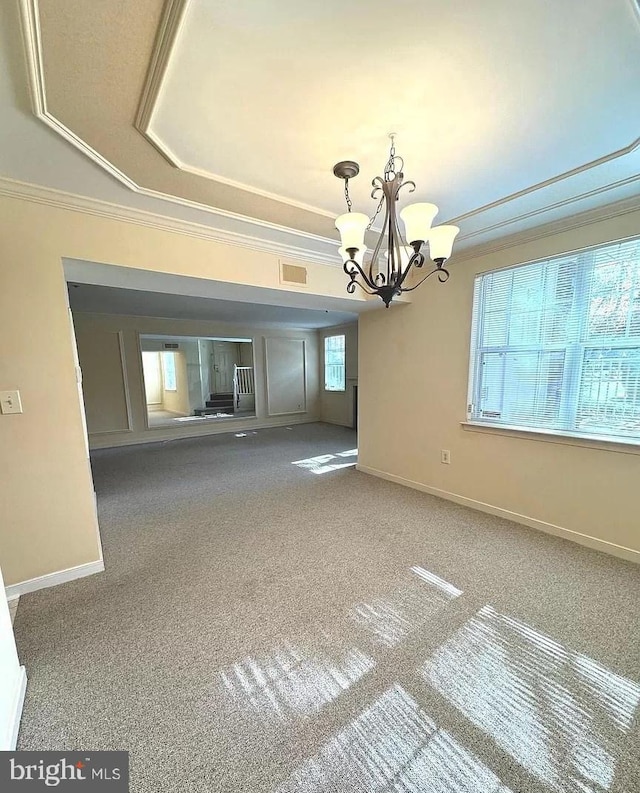 interior space with a raised ceiling, carpet floors, a chandelier, and crown molding