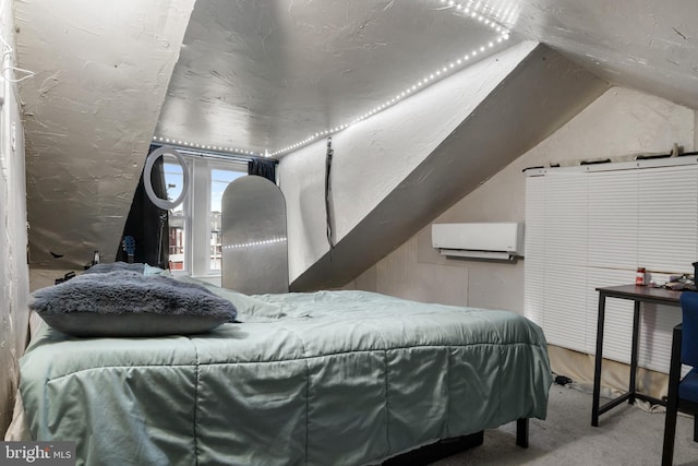 bedroom featuring lofted ceiling, a textured wall, a wall mounted air conditioner, and carpet flooring