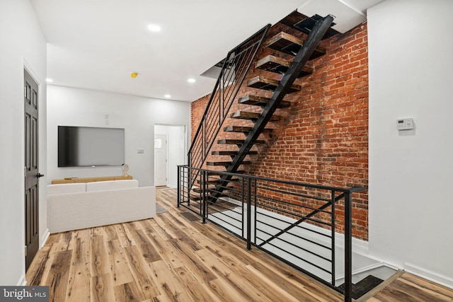 interior space featuring stairs, brick wall, wood finished floors, and recessed lighting