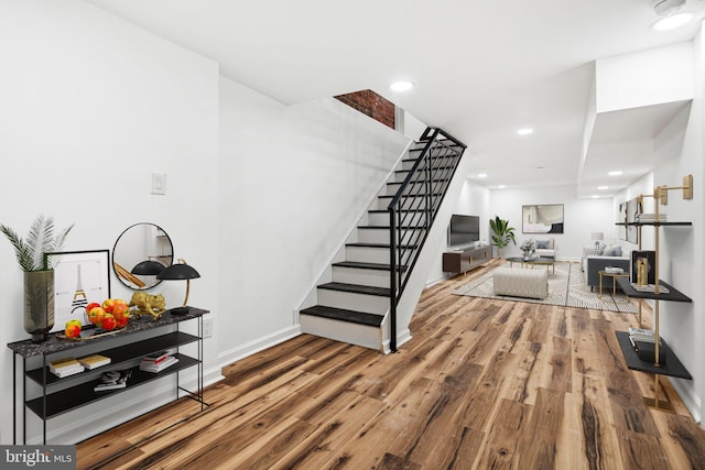 stairway featuring baseboards, wood finished floors, and recessed lighting