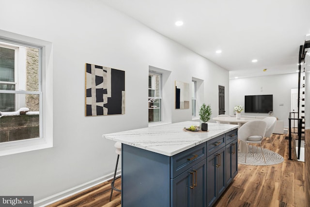 kitchen featuring baseboards, a kitchen island, open floor plan, wood finished floors, and recessed lighting