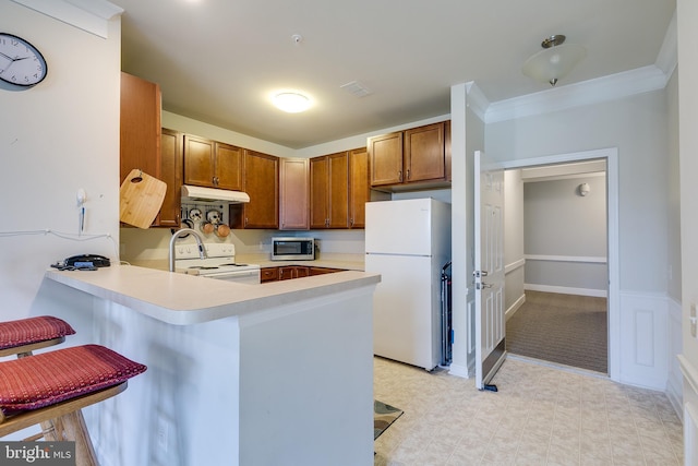 kitchen featuring light countertops, white appliances, a peninsula, and under cabinet range hood