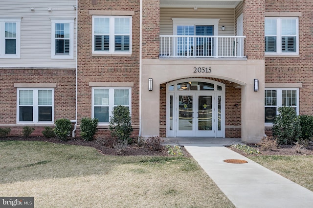 view of exterior entry with a yard, french doors, and brick siding