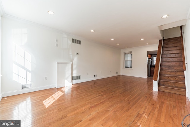 unfurnished living room featuring ornamental molding and light wood-type flooring