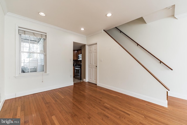 unfurnished living room with ornamental molding and hardwood / wood-style floors