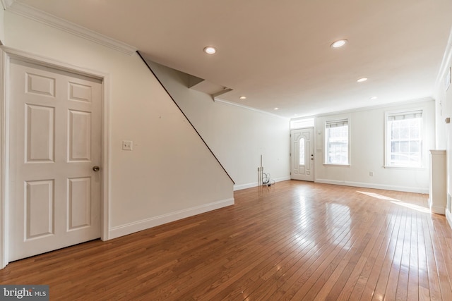 unfurnished living room with wood-type flooring and crown molding