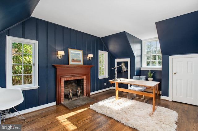 office area featuring a brick fireplace, baseboards, lofted ceiling, and wood finished floors