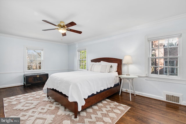 bedroom with a ceiling fan, wood finished floors, visible vents, baseboards, and crown molding