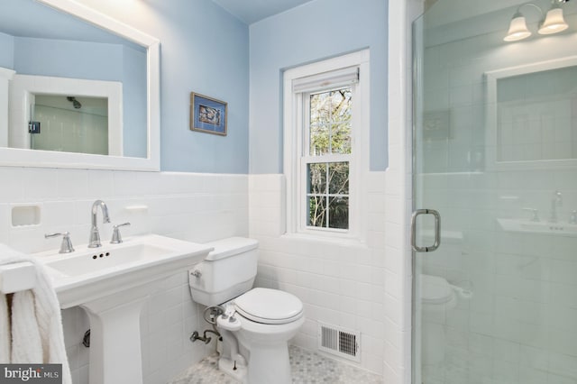 full bath with tile patterned flooring, visible vents, toilet, a stall shower, and tile walls