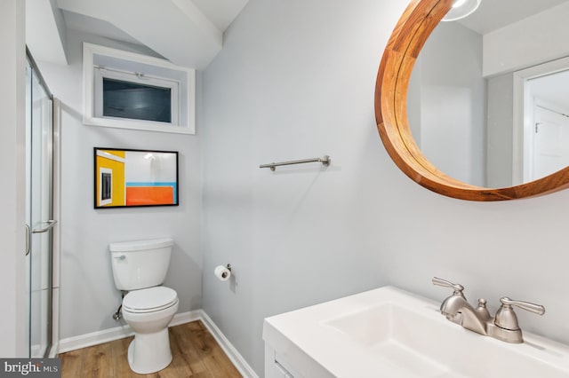 bathroom featuring baseboards, toilet, wood finished floors, a shower with shower door, and vanity