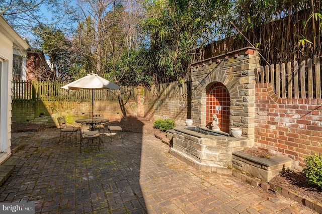 view of patio / terrace with outdoor dining area, an outdoor stone fireplace, and a fenced backyard