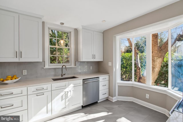 kitchen with a healthy amount of sunlight, a sink, light countertops, dishwasher, and tasteful backsplash