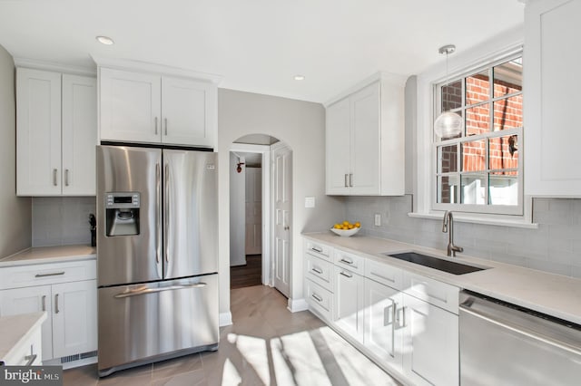 kitchen with a sink, white cabinets, arched walkways, and stainless steel appliances